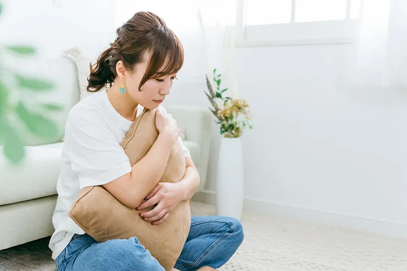 クッションを抱えて座り込む女性